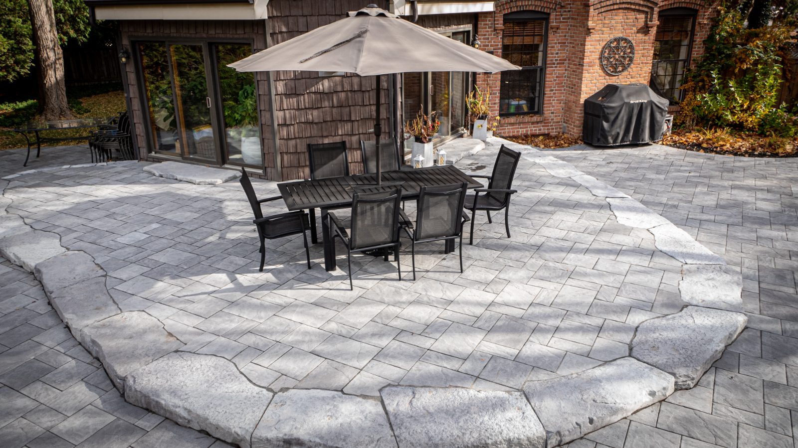 Brown's Concrete Products interlocking stone patio installation with dining set, shot in context